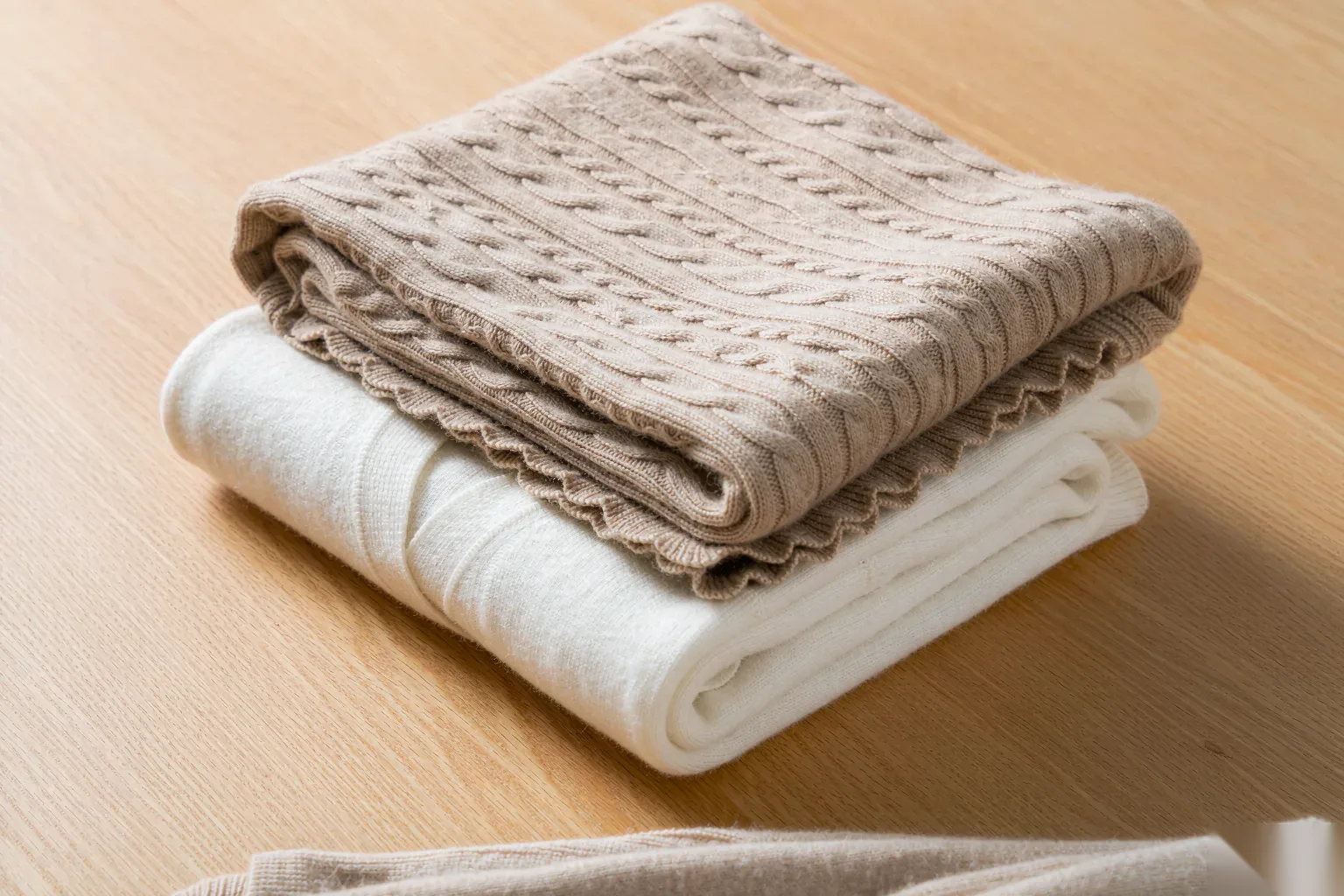 Flat-lay of folded knit sweaters in neutral earth tones